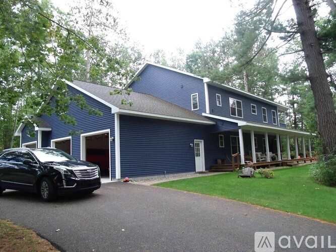 A black car is parked in front of a blue house.