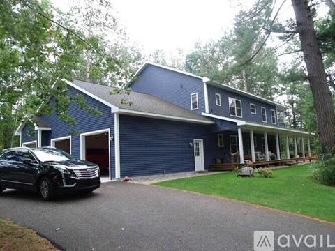 A black car is parked in front of a blue house.