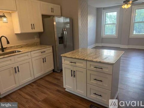 A kitchen with white cabinets and a marble countertop.
