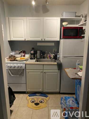 A kitchen with white cabinets and a red microwave.
