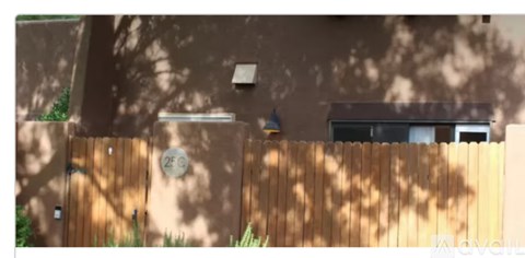 A brown wall with a clock and a wooden fence.