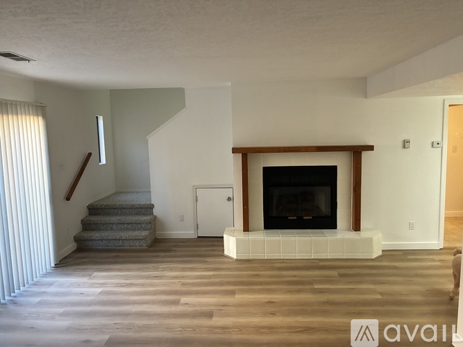 A living room with a fireplace and a staircase.