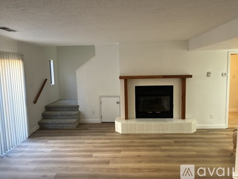 A living room with a fireplace and a staircase.