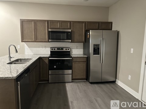 A kitchen with a stove, sink, and refrigerator.