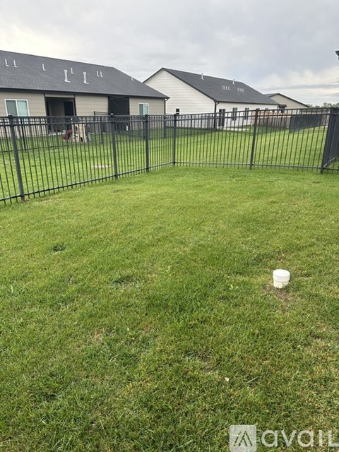A grassy yard with a fence and a house in the background.