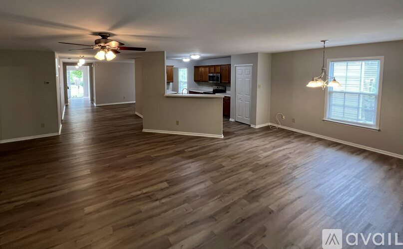 A spacious room with wooden flooring and a ceiling fan.