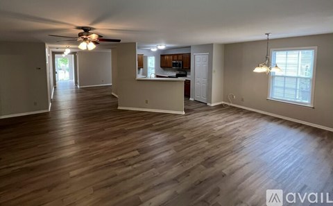 A spacious room with wooden flooring and a ceiling fan.