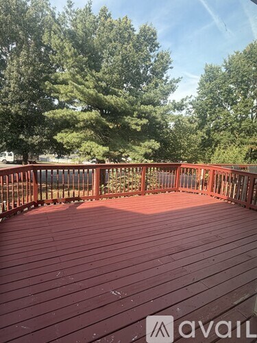 A wooden deck with a railing and trees in the background.