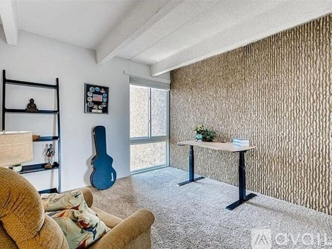 A living room with a couch, a guitar, a table, and a wall with a patterned wallpaper.