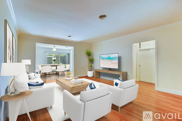 A living room with a white sofa set, a wooden coffee table, and a television on a stand.