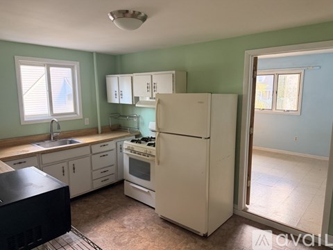 A kitchen with a white refrigerator, sink, and cabinets.