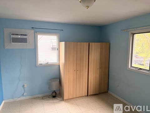 A room with blue walls, a window, a lamp, and a wooden wardrobe.