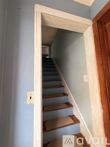 A staircase with a light switch on the wall.