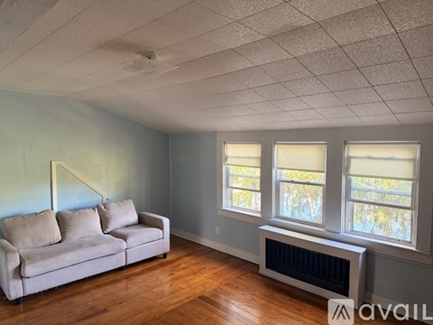 A living room with a couch, a window, and a radiator.