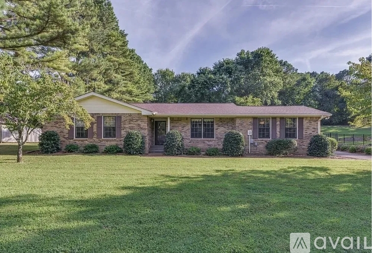 A house with a lawn in front and trees in the background.