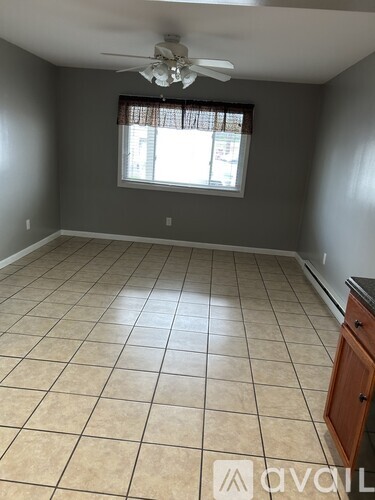 A room with a ceiling fan and a window with blinds.