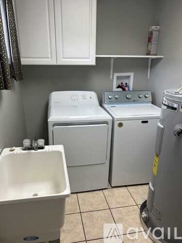 A small laundry room with a washer and dryer and a sink.