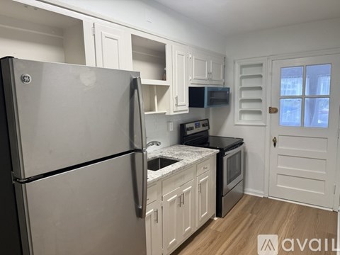 A kitchen with a refrigerator, microwave, oven, and cabinets.