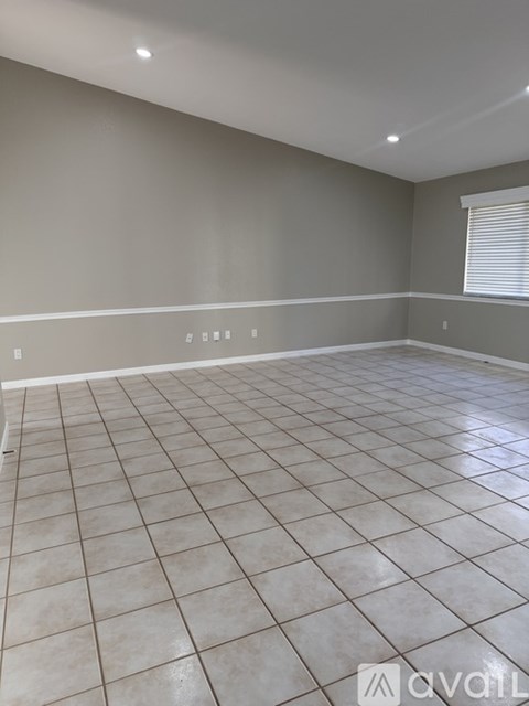 A room with tiled flooring and a window with blinds.