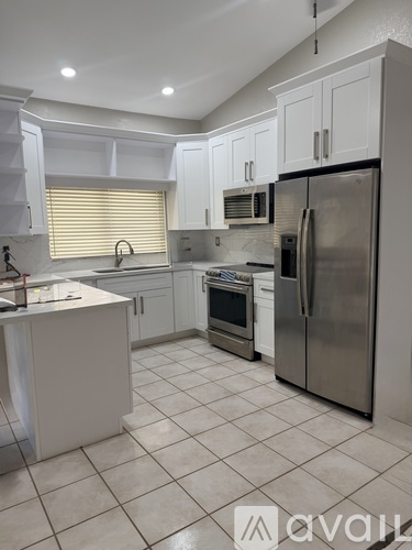 A kitchen with white cabinets and a stainless steel refrigerator.