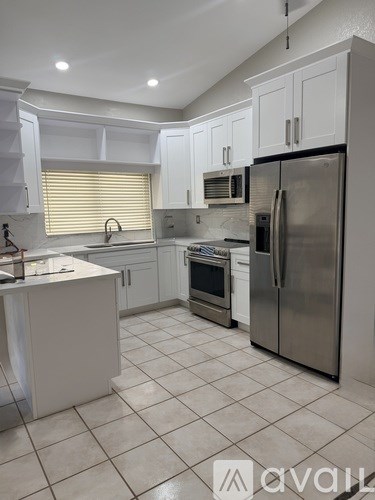 A kitchen with white cabinets and a stainless steel refrigerator.
