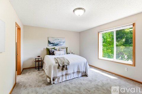 A bedroom with a bed and a window showing greenery outside.