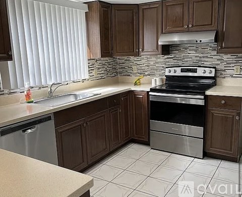 A kitchen with a stove, sink, and cabinets.