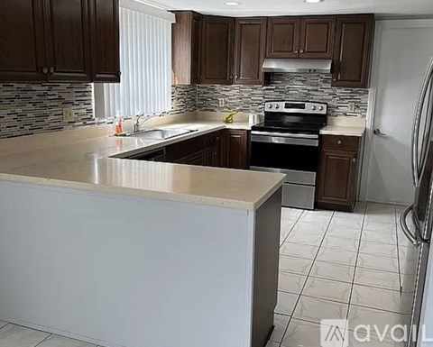 A kitchen with a white countertop and dark brown cabinets.