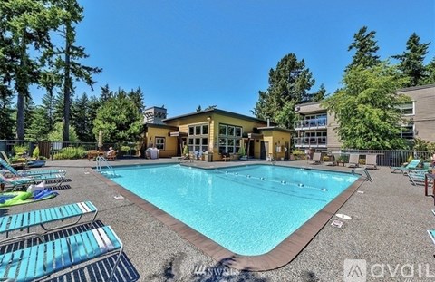 A large swimming pool surrounded by lounge chairs and trees.