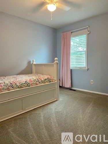 A bedroom with a floral bedspread and a pink curtain.