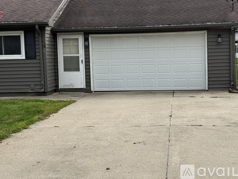 A grey house with a white door and garage door.