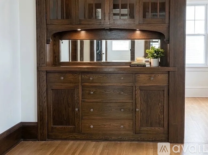 A wooden cabinet with a mirror above it and a plant on top.