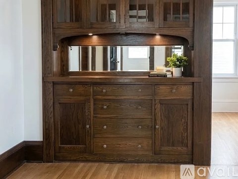 A wooden cabinet with a mirror above it and a plant on top.