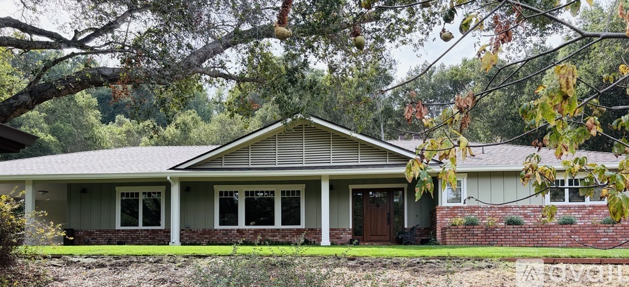 A house with a brown door and windows is surrounded by trees.