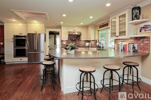 A kitchen with a bar stool in front of a counter.