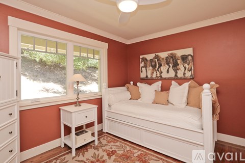 A bedroom with a white bed and a painting of giraffes on the wall.