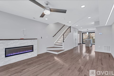 A spacious living room with a fireplace and a staircase leading to the upper floor.