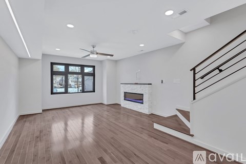A spacious living room with a fireplace and a staircase.