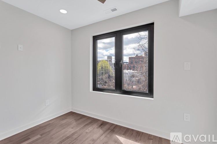 A room with a window showing a view of a tree and buildings outside.