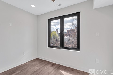 A room with a window showing a view of a tree and buildings outside.