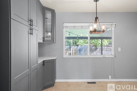 A kitchen with grey cabinets and a hanging light fixture.