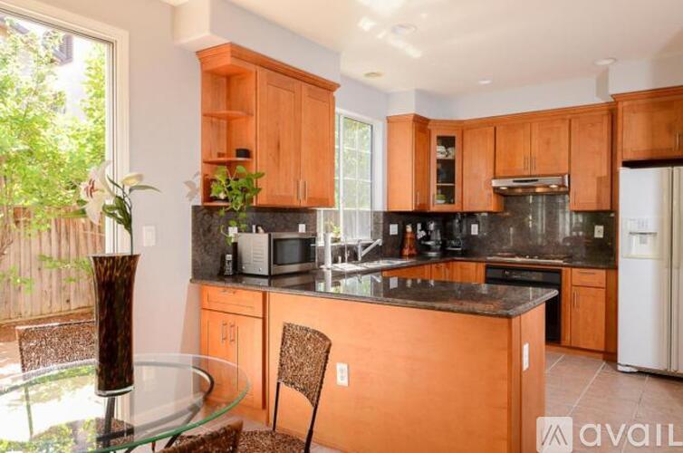 A kitchen with wooden cabinets and a glass table.