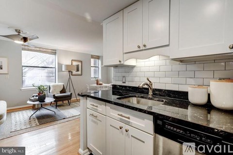 A kitchen with white cabinets and black countertops.