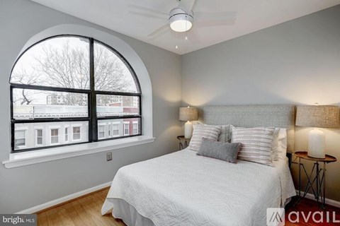 A bedroom with a large bed and a window overlooking a cityscape.
