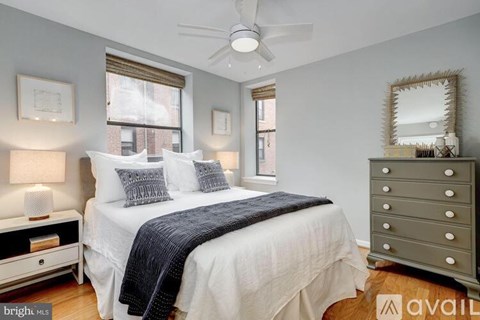 A bedroom with a bed, dresser, and ceiling fan.