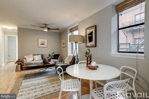 A living room with a white table and chairs, a couch, and a rug.