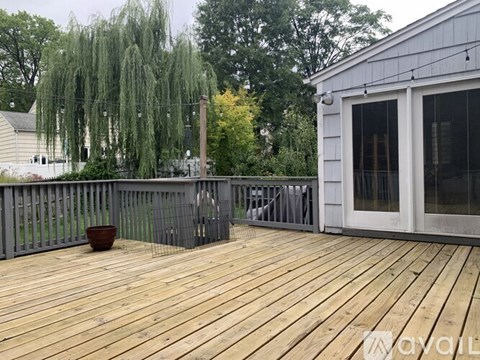 A deck with a wooden floor and a white building in the background.
