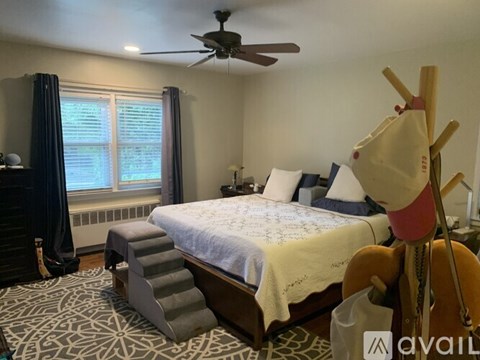 A bedroom with a bed, a ceiling fan, and a window with curtains.