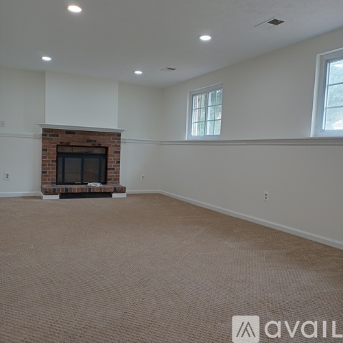 A living room with a fireplace and carpeted floor.