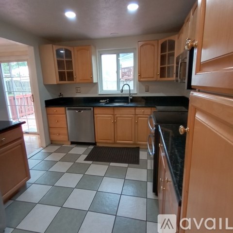 A kitchen with wooden cabinets and black countertops.
